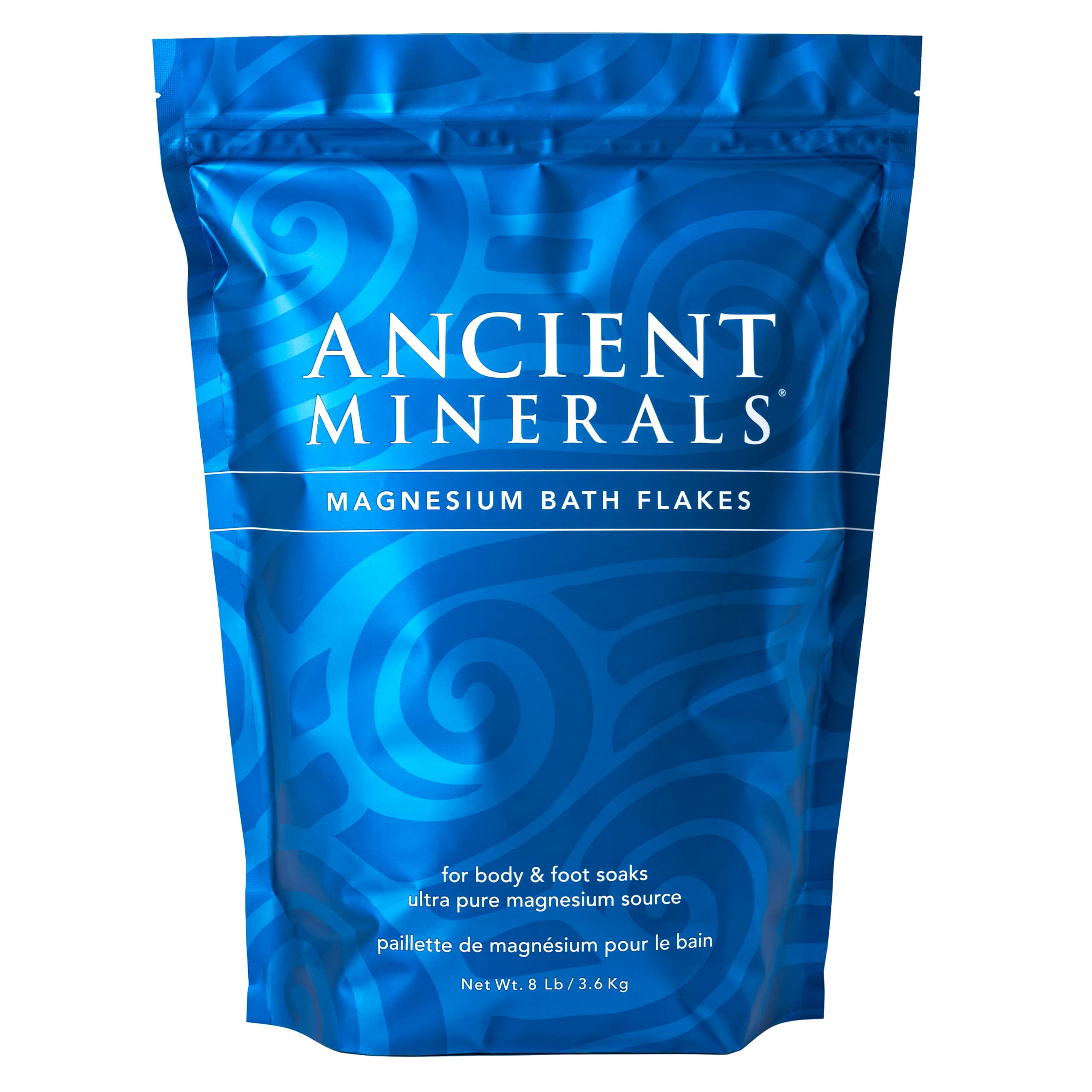 Ancient Minerals Magnesium Bath Flakes in a clear container, showing white mineral flakes for relaxing magnesium baths.