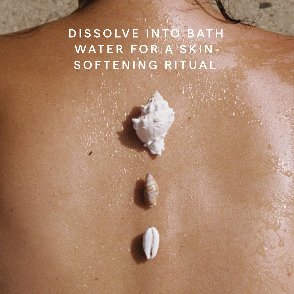 Herbivore Coconut Milk Bath Soak in a clear jar with a scoop, featuring white coconut milk bath salts and natural ingredients.