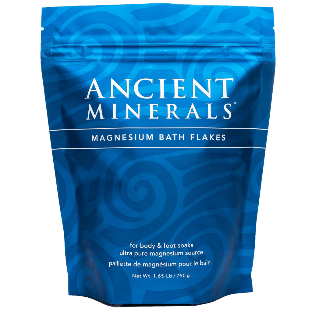 Ancient Minerals Magnesium Bath Flakes in a clear container, showing white magnesium flakes for relaxing bath soaks.