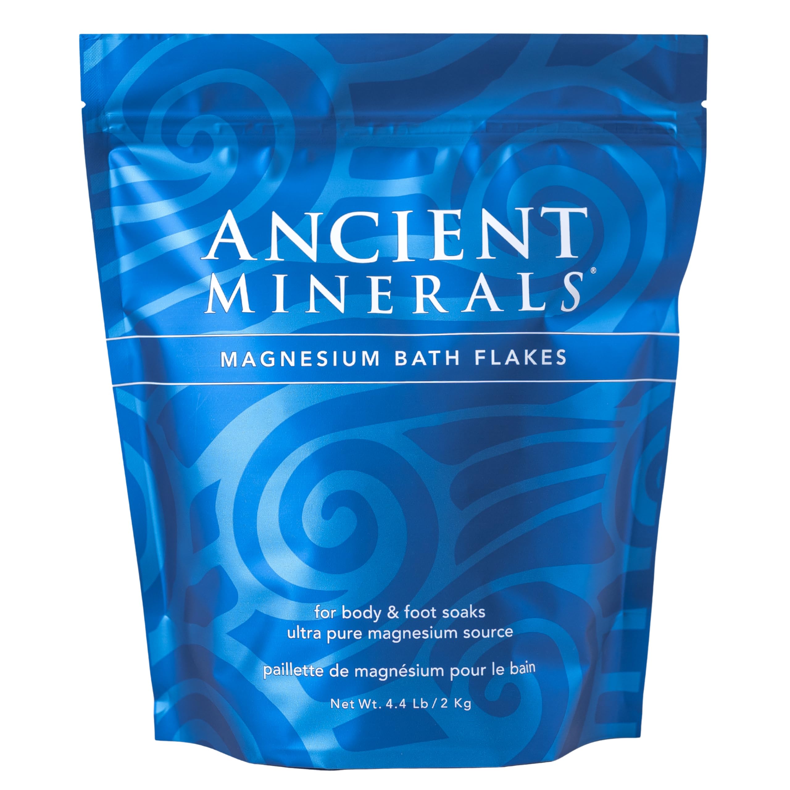 Ancient Minerals Magnesium Bath Flakes in a clear jar, showing flaky magnesium salts for soothing bath relaxation.